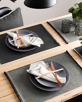 Zwei Tischsets mit Teller, Servietten, Messer und Gabel in gold